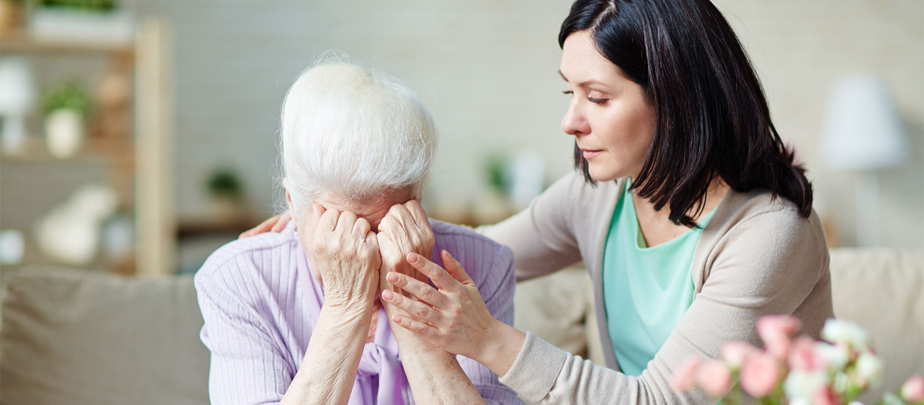Woman consoling elderly woman, who is crying
