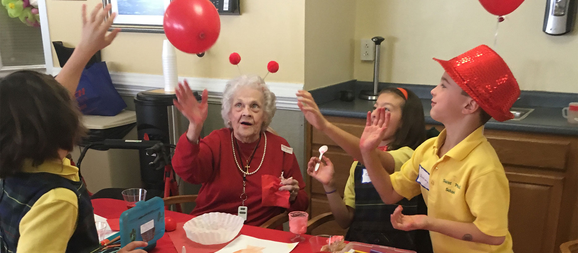 A group of children play with balloons with an elderly woman