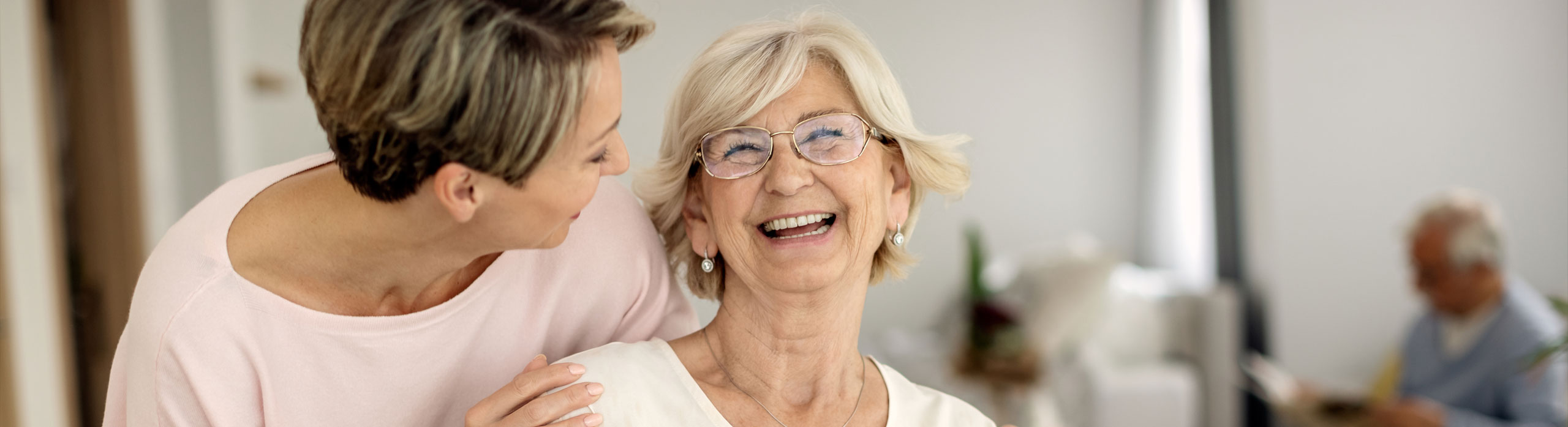 Woman sitting with elderly woman doing crafts